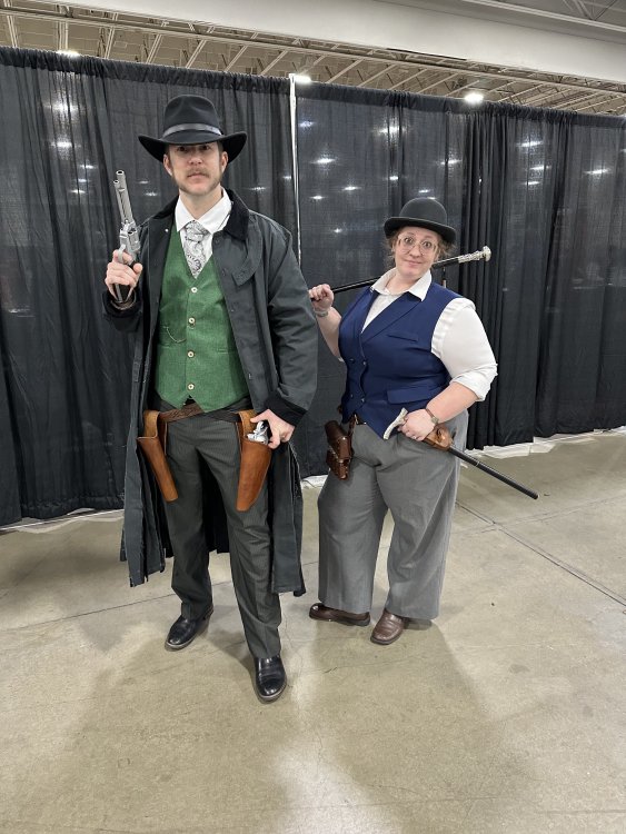 a couple posing dressed as Wax and Wayne from Mistborn Era 3