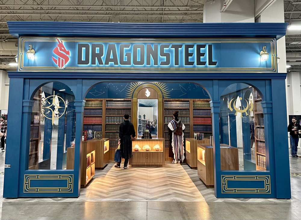 Entrance to the dragonsteel bookstore which looks like a small library in a blue building, with a large "Dragonsteel" sign over the entryway